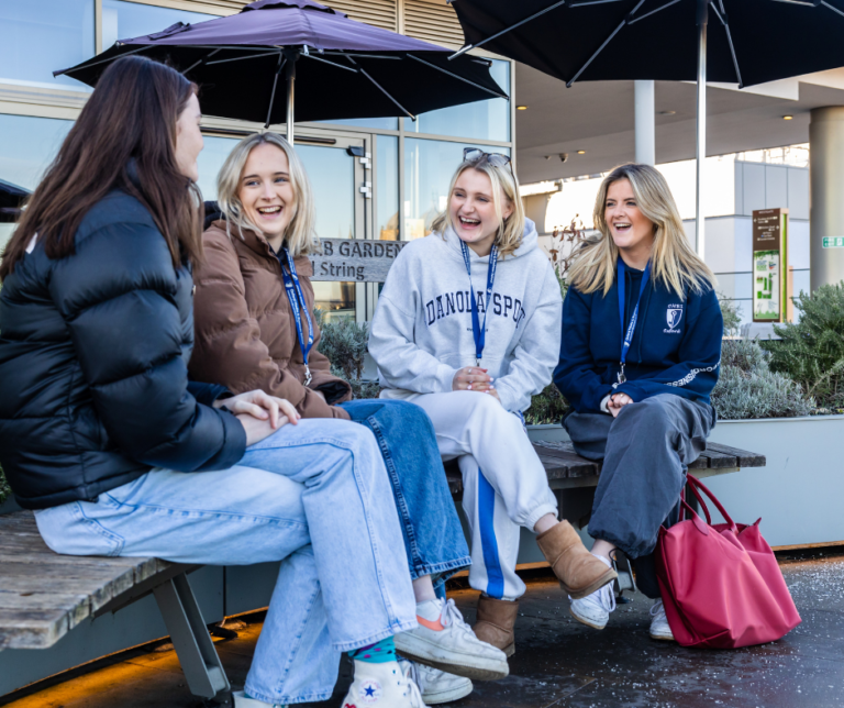 Four young teenage girls sat laughing.