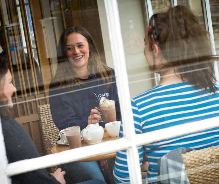 Graduate Careers In Business - three teenages sat in a cafe together smiling