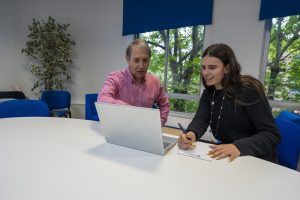 Young female with an adult male tutor, both looking at the laptop.