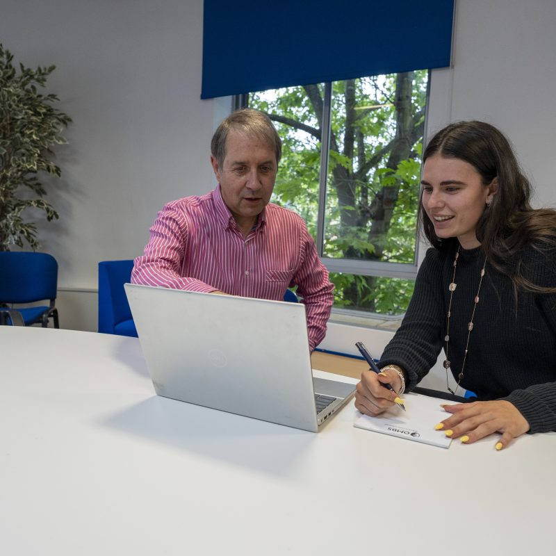 Young female with an adult male tutor, both looking at the laptop.