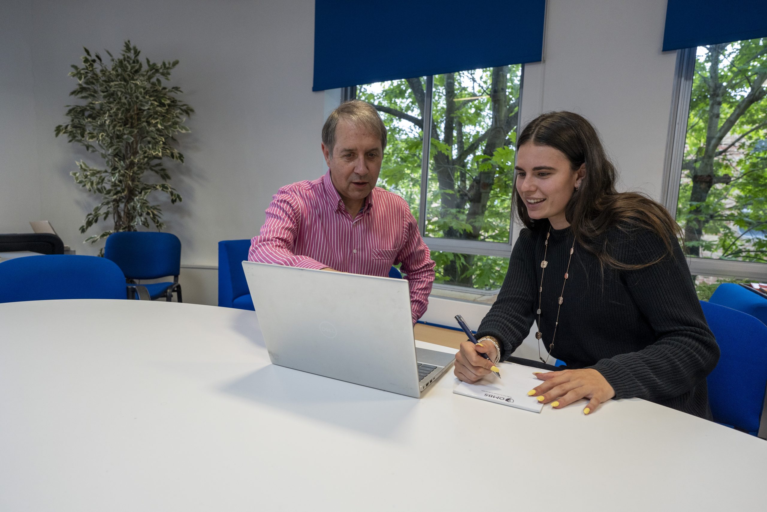 Young female with an adult male tutor, both looking at the laptop.